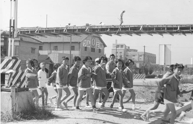 17 昭和37年 浜脇小学校近くを横断する児童と建設中の歩道橋