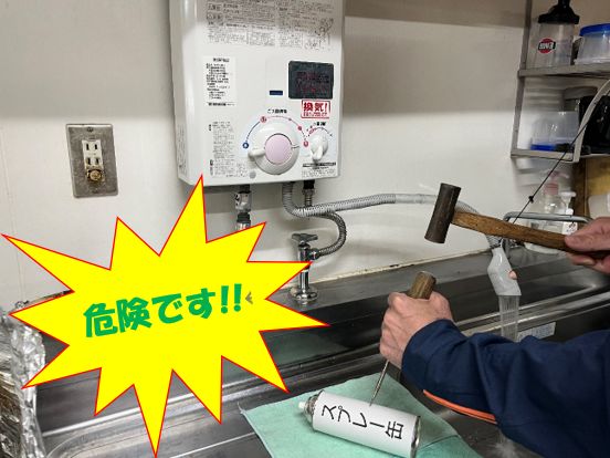 点火中ガス給湯器の前でスプレー缶のガス抜きをしている画像