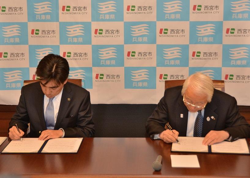 協定書にサインをする井戸県知事と石井西宮市長