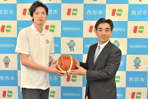 西宮ストークスの主将から石井市長がサイン入りバスケットボールを贈呈される様子